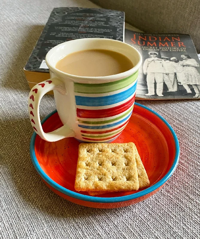 Festive holiday-themed mugs-Stripes n heart Gloria mug with bright orange snacking plate.